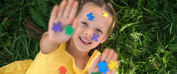child laying in grass holding puzzle pieces
